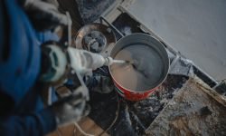 Construction worker mixing epoxy resin in a bucket, preparing it for floor coating
