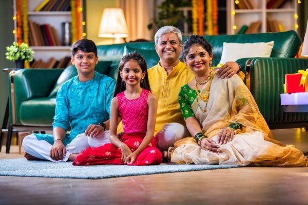 Indian family of four sitting with gift boxes on sofa in diwali festival