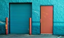 Vivid blue wall with a closed door and shutter in Valparaiso's urban setting.